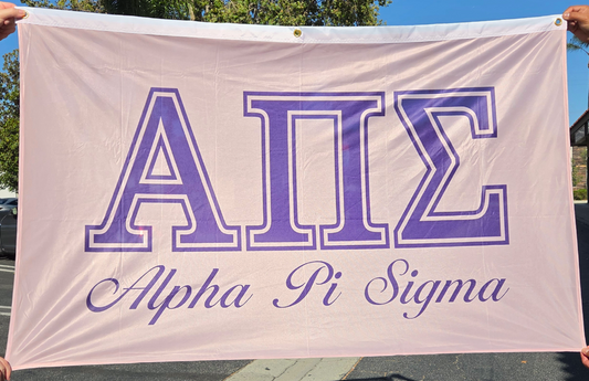 A light pink Alpha Pi Sigma banner held up outdoors by hands at the corners, featuring the Greek letters 'ΑΠΣ' in purple with white outlines and the words 'Alpha Pi Sigma' in purple script below.