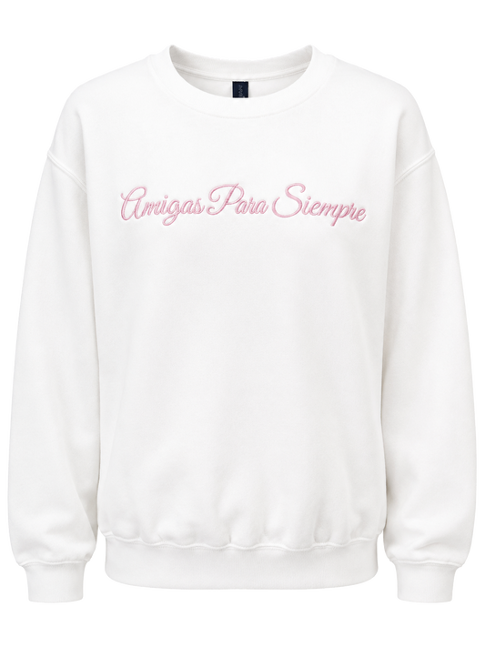 A white crewneck sweatshirt with 'Amigas Para Siempre' embroidered in pink cursive across the chest, shown against a plain white background.